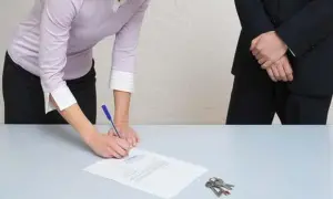 Une femme signe un document, peut-être un modèle lettre demande pour préjudice subi. Des clés sont posées sur la table.