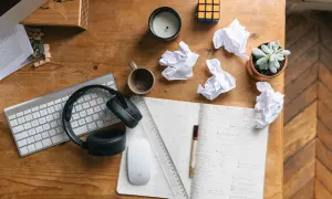 Bureau de travail avec clavier, casque, souris, carnet, brouillons et plante. Idéal pour rédiger une lettre de motivation fonction publique territoriale.