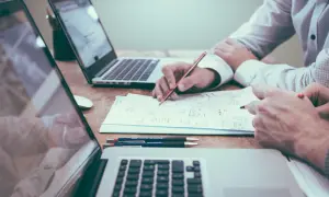 Deux personnes travaillent sur un projet, l'une rédigeant une lettre de motivation pour licence pro sur un ordinateur portable.