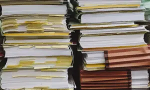 Piles of documents, some with yellow tabs, suggest a complex administrative process, perhaps a demande de relevé de carrière par courrier.
