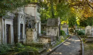 Allée pavée dans un cimetière verdoyant, bordée de mausolées. Idéal pour un modèle de lettre pour renouvellement de concession cimetière.