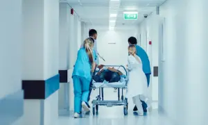 Équipe médicale transportant un patient sur un brancard dans un couloir d'hôpital. Idéal pour une lettre de motivation brancardier sans expérience.