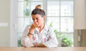 Femme pince son nez, visiblement incommodée par des nuisances olfactives. Elle prépare peut-être une lettre au maire.