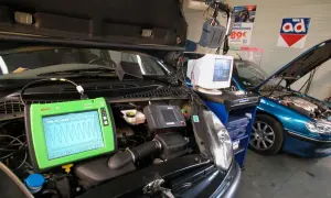 Diagnostic automobile chez Opel France. Un écran Bosch affiche des courbes, une voiture bleue est en réparation.