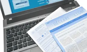 Documents fiscaux sur un ordinateur portable, dont une déclaration de revenus et un guide pour la lettre changement adresse impots.