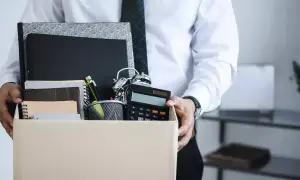 Un étudiant quitte son emploi, portant une boîte remplie d'objets de bureau, symbolisant une lettre de démission contrat étudiant sans préavis.