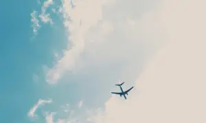 Un avion Volotea, peut-être en retard, traverse un ciel bleu parsemé de nuages cotonneux.