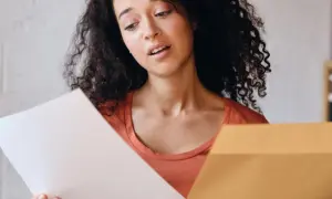 Jeune femme perplexe devant sa lettre de motivation Parcoursup. Elle tient un document blanc et une enveloppe marron.