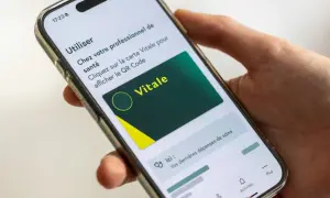 Main d'une personne tenant un smartphone affichant la carte Vitale numérique. Idéal pour le courrier restitution carte vitale.