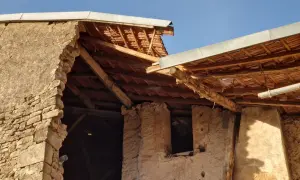Mise en demeure : mur écroulé du voisin. Bâtiment en ruine, toiture endommagée, ciel bleu.