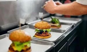 Trois hamburgers appétissants sur des plateaux, prêts pour la livraison. Une image parfaite pour une lettre de motivation restauration rapide.