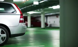 Voiture argentée dans un parking souterrain. Le sol est vert vif. On dirait que le propriétaire prépare une lettre préavis garage 1 mois.