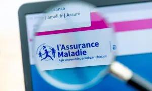 Loupe sur l'écran d'un ordinateur affichant le site ameli.fr, logo de l'Assurance Maladie. Une lettre demande d'ouverture des droits à l'assurance maladie est en cours de consultation.