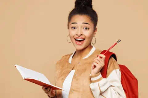 Jeune femme souriante avec un livre et un crayon, prête pour sa lettre de motivation stage à l'étranger.