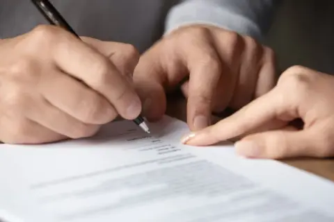 Signature sur un document, peut-être une lettre recommandée pour un préavis.