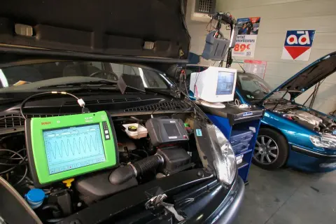 Diagnostic automobile chez Opel France. Un écran Bosch affiche des courbes, une voiture bleue est en réparation.