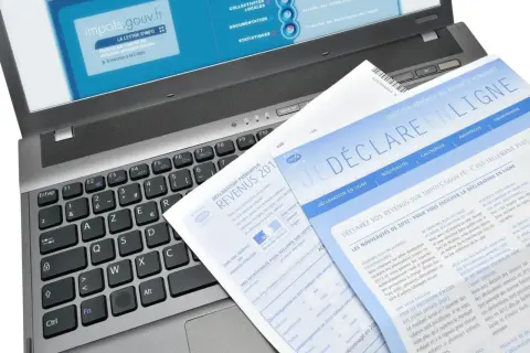 Documents fiscaux sur un ordinateur portable, dont une déclaration de revenus et un guide pour la lettre changement adresse impots.
