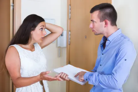 Un homme explique à une voisine comment faire une pétition de voisinage. Elle semble surprise et perplexe.