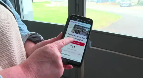 Une personne consulte sur son téléphone un modèle pétition locataires sur Change.org, demandant des logements dignes.