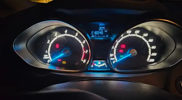 Tableau de bord d'une Ford, allumé la nuit. Le kilométrage est de 218048 km. Cela pourrait servir de preuve pour une lettre de réclamation Ford France.