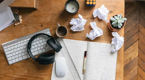 Bureau de travail avec clavier, casque, souris, carnet, brouillons et plante. Idéal pour rédiger une lettre de motivation fonction publique territoriale.