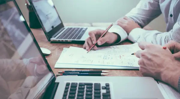 Deux personnes travaillent sur un projet, l'une rédigeant une lettre de motivation pour licence pro sur un ordinateur portable.