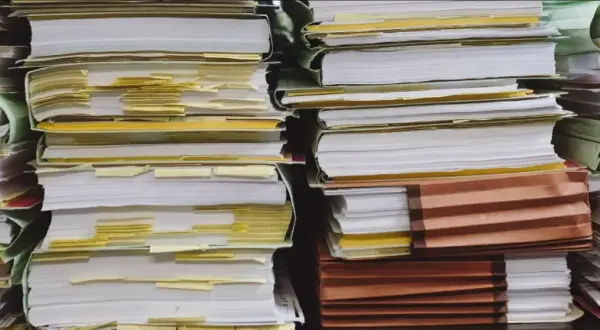 Piles of documents, some with yellow tabs, suggest a complex administrative process, perhaps a demande de relevé de carrière par courrier.