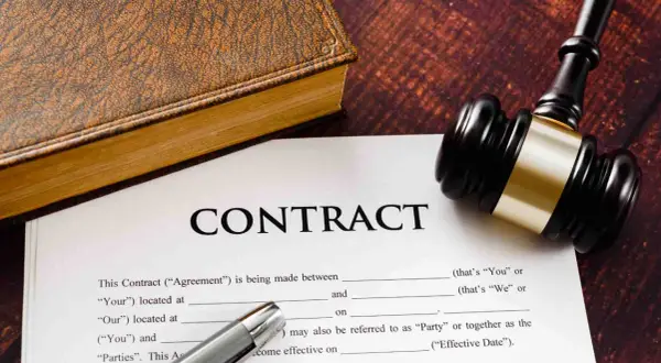 Un contrat, un livre ancien et un maillet de juge. Un exemple de lettre de fin de mission pour un contrat.