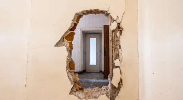 Trou dans un mur révélant une porte. Idéal pour un modèle lettre logement insalubre.