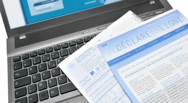 Documents fiscaux sur un ordinateur portable, dont une déclaration de revenus et un guide pour la lettre changement adresse impots.
