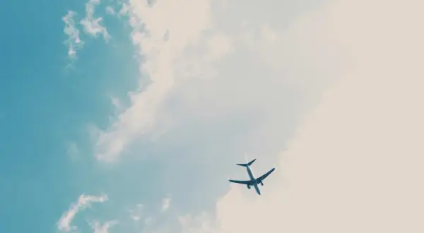 Un avion Volotea, peut-être en retard, traverse un ciel bleu parsemé de nuages cotonneux.