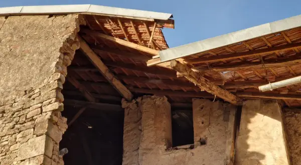 Mise en demeure : mur écroulé du voisin. Bâtiment en ruine, toiture endommagée, ciel bleu.