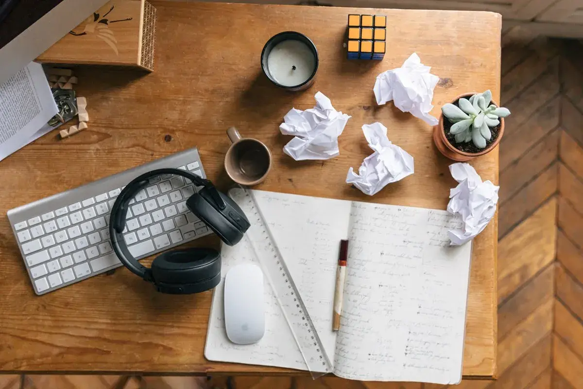 Bureau de travail avec clavier, casque, souris, carnet, brouillons et plante. Idéal pour rédiger une lettre de motivation fonction publique territoriale.