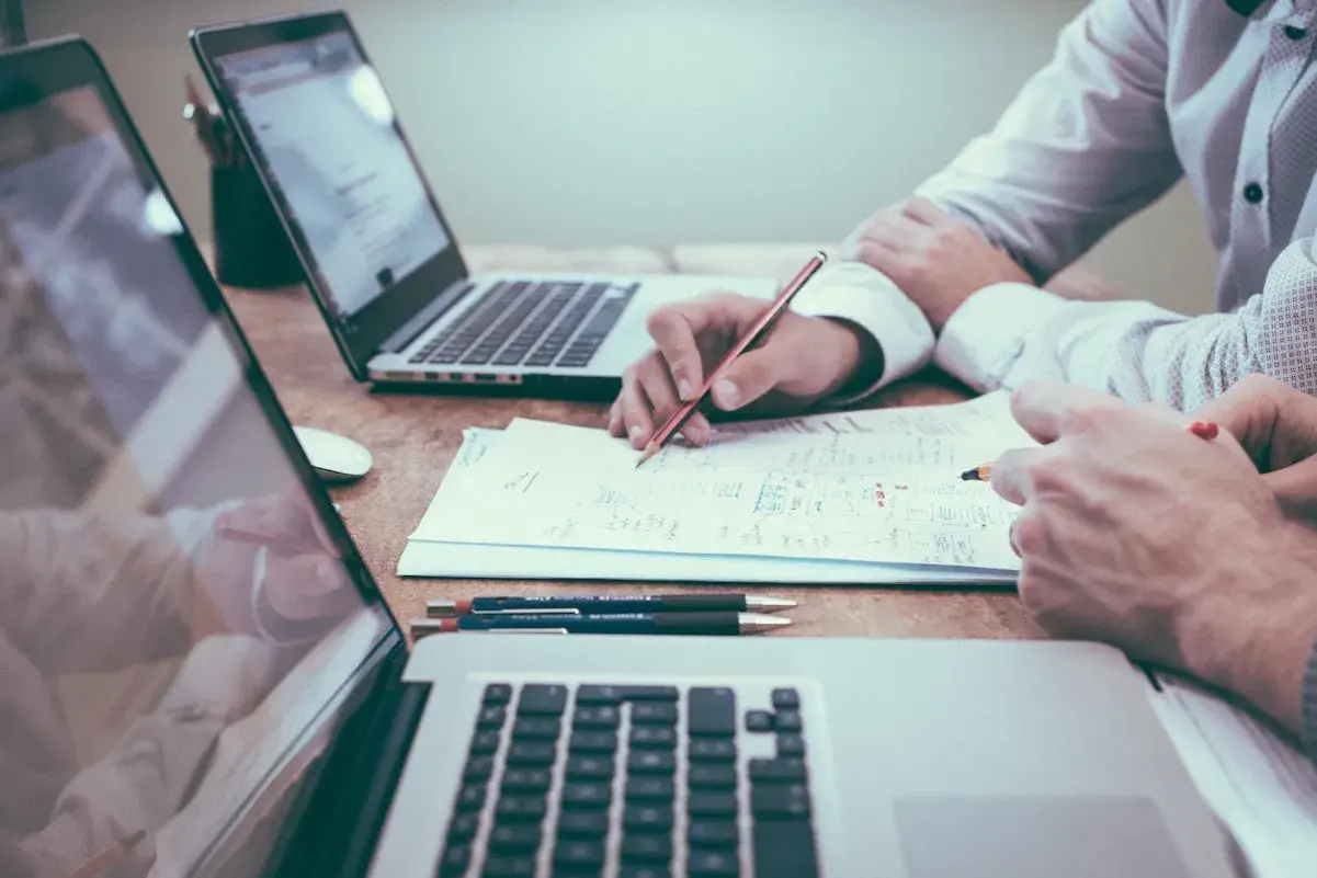 Deux personnes travaillent sur un projet, l'une rédigeant une lettre de motivation pour licence pro sur un ordinateur portable.