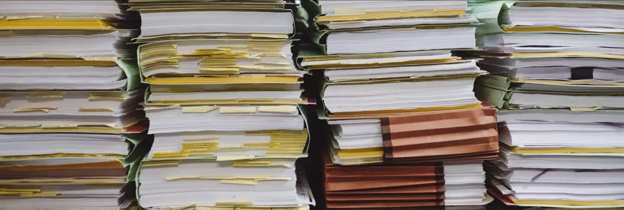 Piles of documents, some with yellow tabs, suggest a complex administrative process, perhaps a demande de relevé de carrière par courrier.