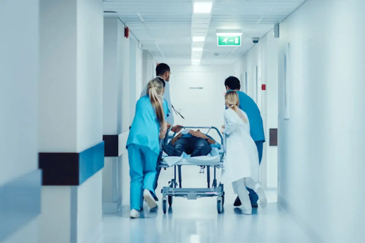 Équipe médicale transportant un patient sur un brancard dans un couloir d'hôpital. Idéal pour une lettre de motivation brancardier sans expérience.