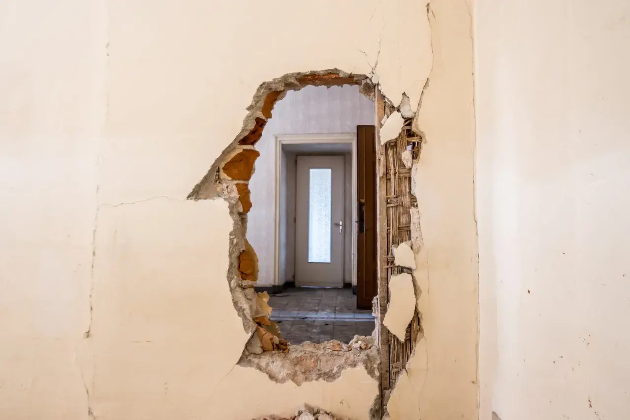 Trou dans un mur révélant une porte. Idéal pour un modèle lettre logement insalubre.