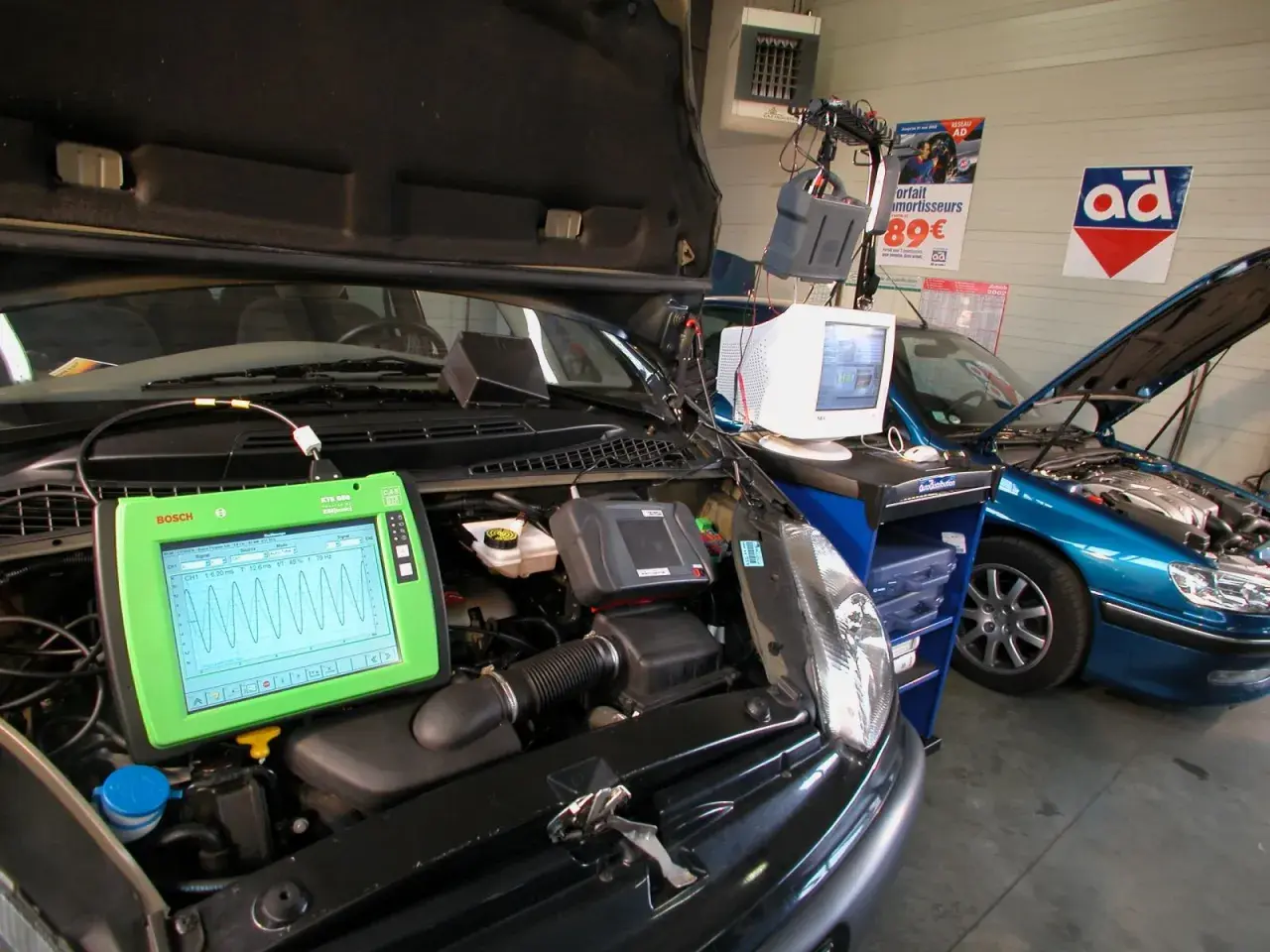 Diagnostic automobile chez Opel France. Un écran Bosch affiche des courbes, une voiture bleue est en réparation.