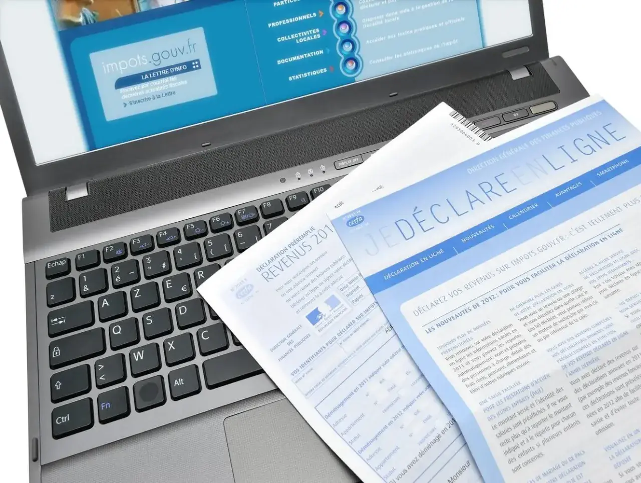 Documents fiscaux sur un ordinateur portable, dont une déclaration de revenus et un guide pour la lettre changement adresse impots.