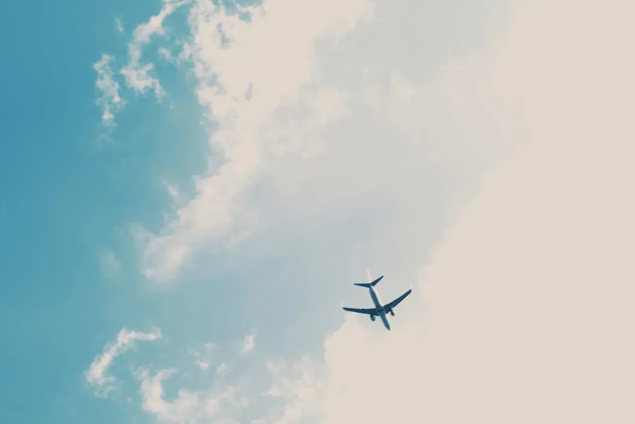 Un avion Volotea, peut-être en retard, traverse un ciel bleu parsemé de nuages cotonneux.