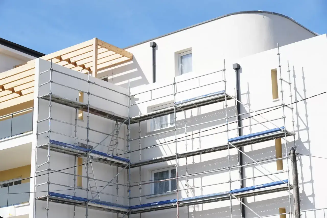 Immeuble blanc en construction avec échafaudages. Idéal pour un modèle lettre bailleur sociaux pour travaux.