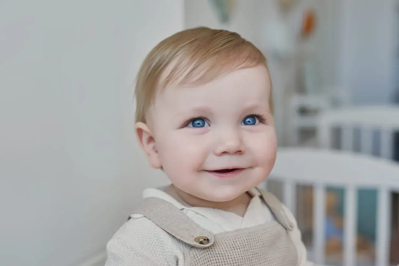 Un bébé aux yeux bleus pétillants sourit, prêt pour sa lettre demande de place en crèche urgent.
