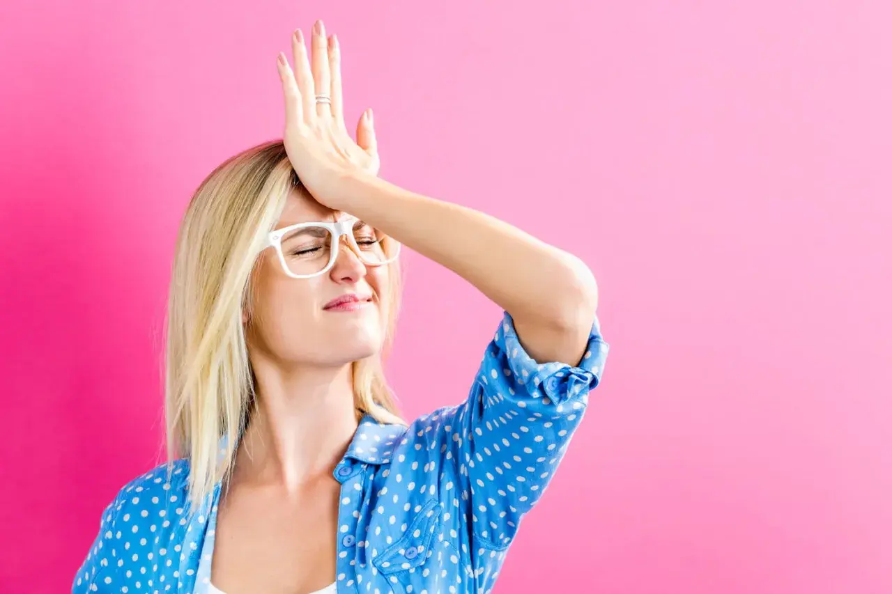 Oups, j'ai oublié de signer la lettre de désolidarisation de bail ! Cette femme se frappe le front, l'air désemparé, sur fond rose.