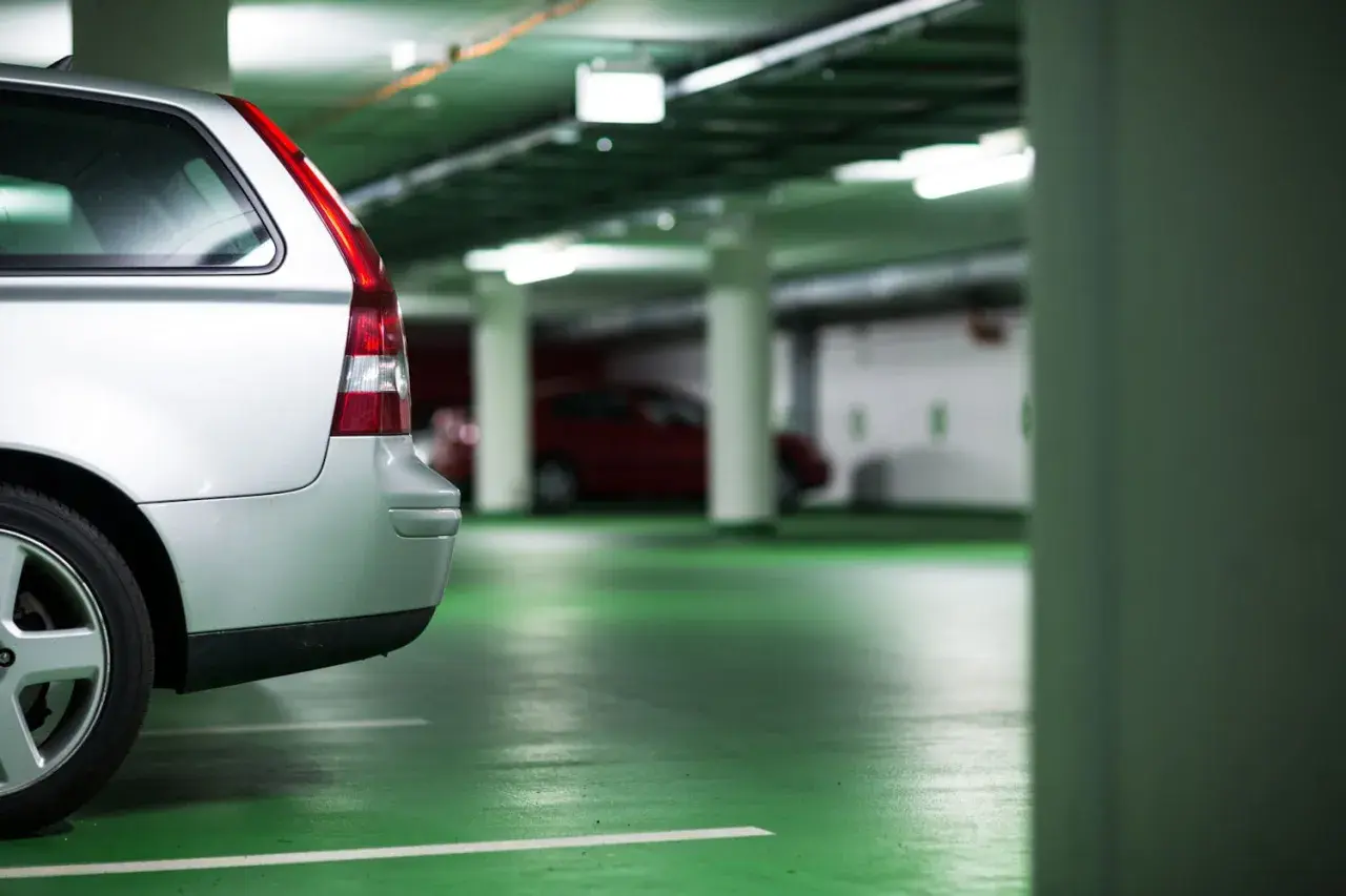 Voiture argentée dans un parking souterrain. Le sol est vert vif. On dirait que le propriétaire prépare une lettre préavis garage 1 mois.