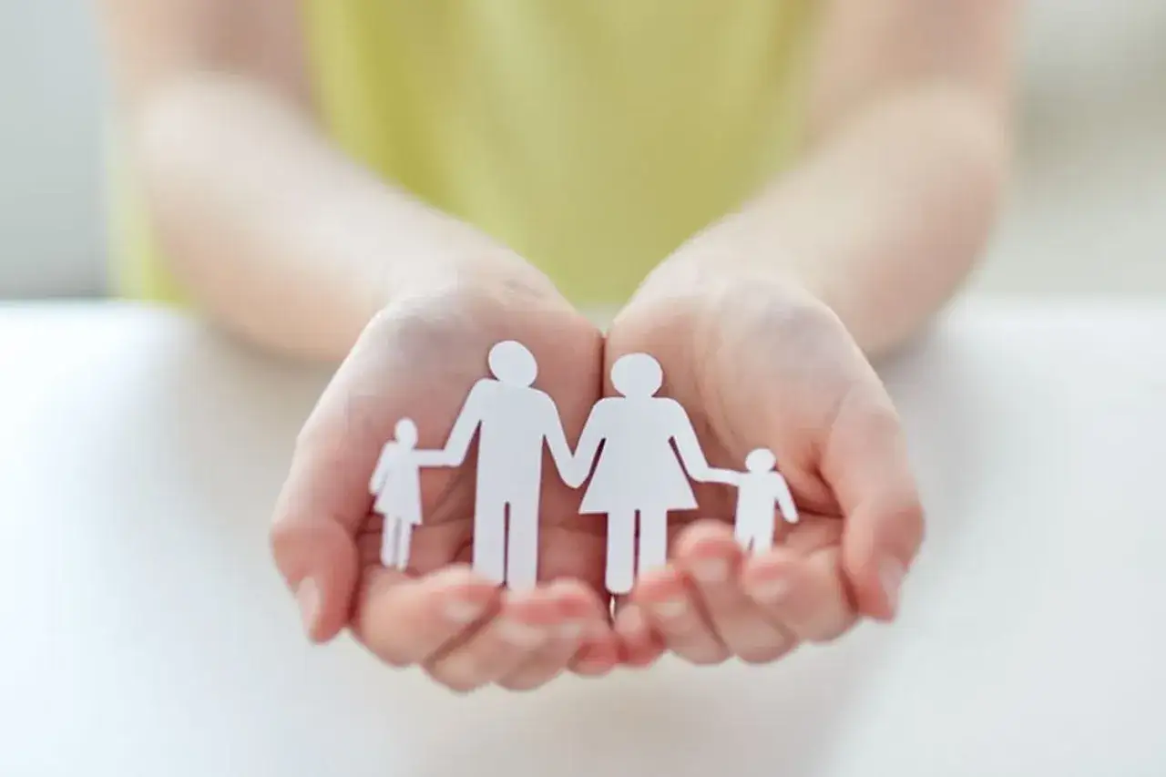 Mains tenant une famille en papier, symbole d'une lettre de demande d'agr&eacute;ment adoption.