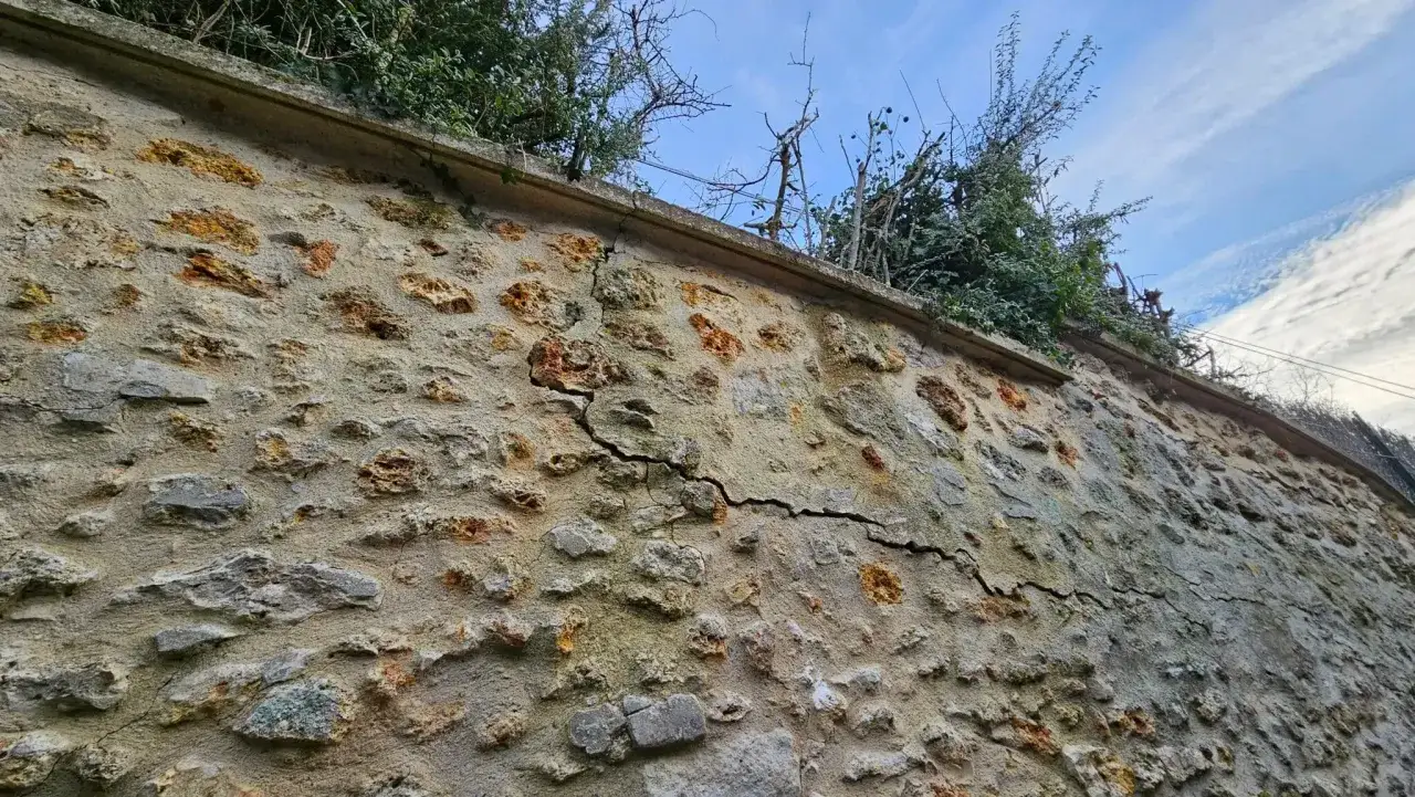 Mur en pierre fissuré, rappelant la nécessité d'une mise en demeure pour le mur écroulé du voisin.