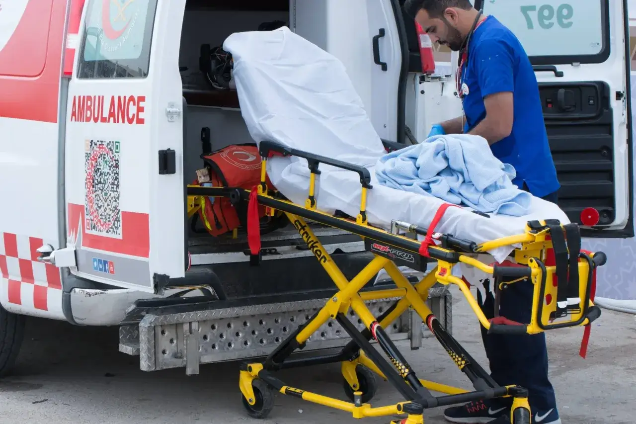 Un brancardier sans expérience prépare une civière devant une ambulance. Il est prêt à aider, comme dans une lettre de motivation brancardier sans expérience.