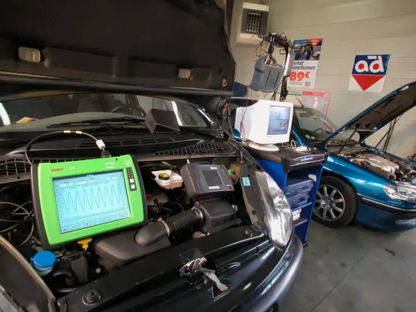 Diagnostic automobile chez Opel France. Un écran Bosch affiche des courbes, une voiture bleue est en réparation.