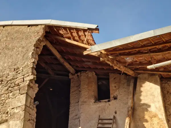 Mise en demeure : mur écroulé du voisin. Bâtiment en ruine, toiture endommagée, ciel bleu.